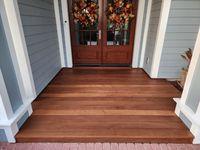 Warm-toned wooden porch floor with a rich finish leading to an inviting double door entryway, displaying expert deck construction in Palm Bay, Florida.