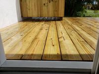 Handcrafted composite deck next to a house in an outdoor living space with a dog standing on top of the deck