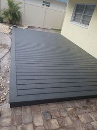 Robust charcoal black composite deck seamlessly adjoining a paver patio, displaying the durability and style of custom-built decks in Palm Bay, FL.
