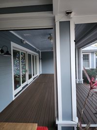 View of a spacious composite deck from the porch, with a glimpse of festive lights through the windows, by Palm Bay's exterior renovation specialists.