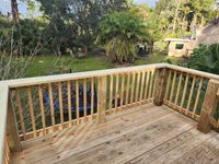 Elevated natural wood deck with railings offering a view of a lush backyard, showcasing the integration of outdoor structures with the Florida landscape.