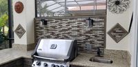 Sophisticated screened-in outdoor kitchen with brick backsplash and top-of-the-line grill, highlighting luxury outdoor living in Palm Bay, FL.