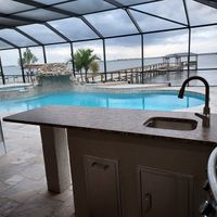 Luxurious poolside outdoor kitchen with a built-in sink and spacious countertops, enhancing backyard entertainment in a Florida home by expert pergola and pavilion builders.