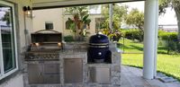 Inviting outdoor kitchen setting with grill ready to entertain, situated in a lush green Florida backyard with lake view