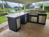 Sleek outdoor kitchen setup with a premium stainless steel BBQ grill and refrigeration, overlooking a serene backyard pond in Brevard County, by top local outdoor living specialists.