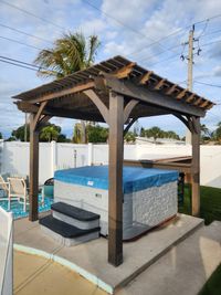 Elegant spa pavilion with a dark-stained wooden frame, covering a hot tub in a residential backyard in Brevard County, FL.