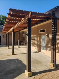 Stylish elongated wooden pergola attached to a house providing shaded outdoor space, with modern vertical privacy screens in Palm Bay, Florida.