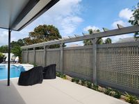 Contemporary backyard with a sleek pergola and privacy lattice panels, complementing a poolside setting for a Palm Bay residence.