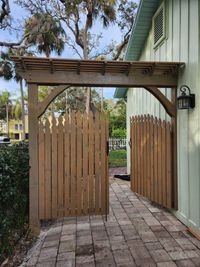Charming wooden entry arbor with a picket fence, showcasing the craftsmanship of Palm Bay's trusted outdoor living construction services.
