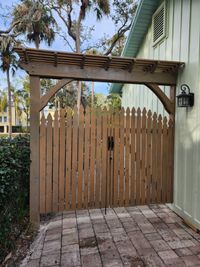 Wooden gate with pergola top in Palm Bay, adding classic charm to a home's entrance with expert construction services from Brevard County's exterior specialists.