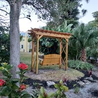 Cozy garden nook with a wooden pergola and bench in Brevard County, constructed by Palm Bay's premier outdoor living specialists.