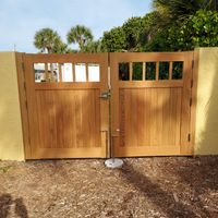 Warm-toned wooden double gates standing at the entrance to a tropical Florida home's garden, offering privacy and style.