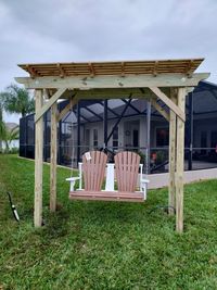 Rustic wooden swing bench under a simple pergola, offering a serene seating area in a green Floridian backyard.