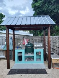 Compact outdoor grill station with a metal roof and vibrant teal finish, showcasing innovative small-space solutions by Palm Bay's exterior experts.