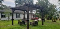 Elegant dark-stained pergola with comfortable outdoor furniture, creating a perfect backyard retreat in Palm Bay, FL.