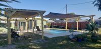 Spacious backyard with a dual pergola setup framing a swimming pool, showcasing Palm Bay's custom deck and pergola craftsmanship.