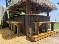 Rustic beachside tiki bar with natural thatched roof and wooden counters, demonstrating Palm Bay's creativity in outdoor entertainment spaces.
