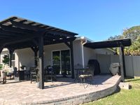Spacious patio area with a large pergola providing ample shade over outdoor furniture, demonstrating Palm Bay's expertise in outdoor living spaces.