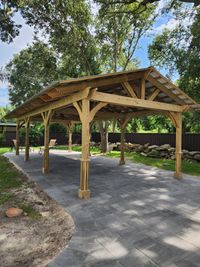 Vast covered pavilion with open wooden beams and stone flooring, perfect for gatherings, built by Brevard County's premier outdoor construction firm.