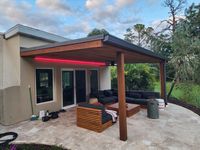 Modern outdoor living space with sleek furniture under a pergola with red accent lighting, highlighting luxury exteriors in Palm Bay.