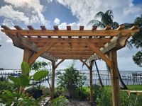 Lakefront garden view under a classic wooden pergola with sturdy beams, nestled among vibrant foliage in Brevard County, FL.