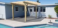 Modern composite deck with a wooden pergola addition enhancing a poolside area in a Palm Bay, Florida home.