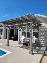 Modern gray pergola with louvered roof over an outdoor dining set, exemplifying Palm Bay's exterior design and construction expertise.